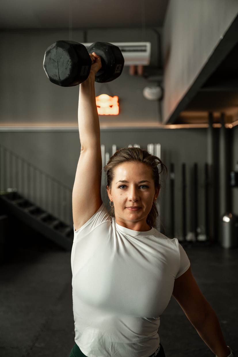 Athletin drückt eine Kurzhantel über den Kopf